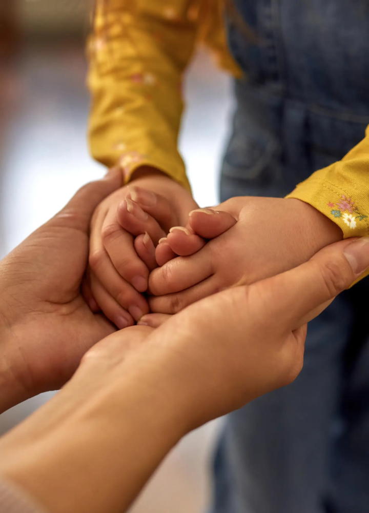 An adult holding a child’s hands