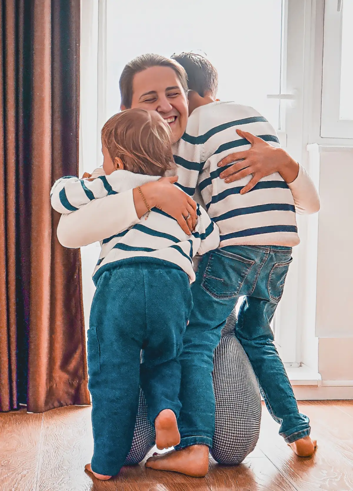 A smiling parent embracing two children