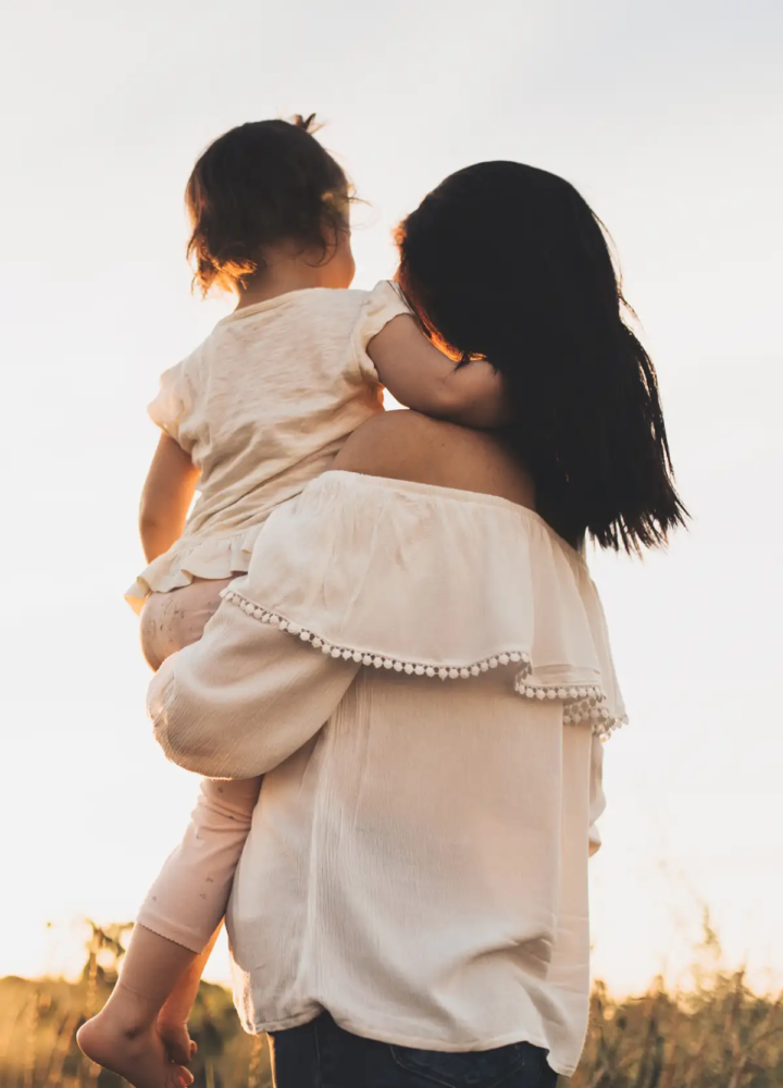 A parent carrying a young child outdoors